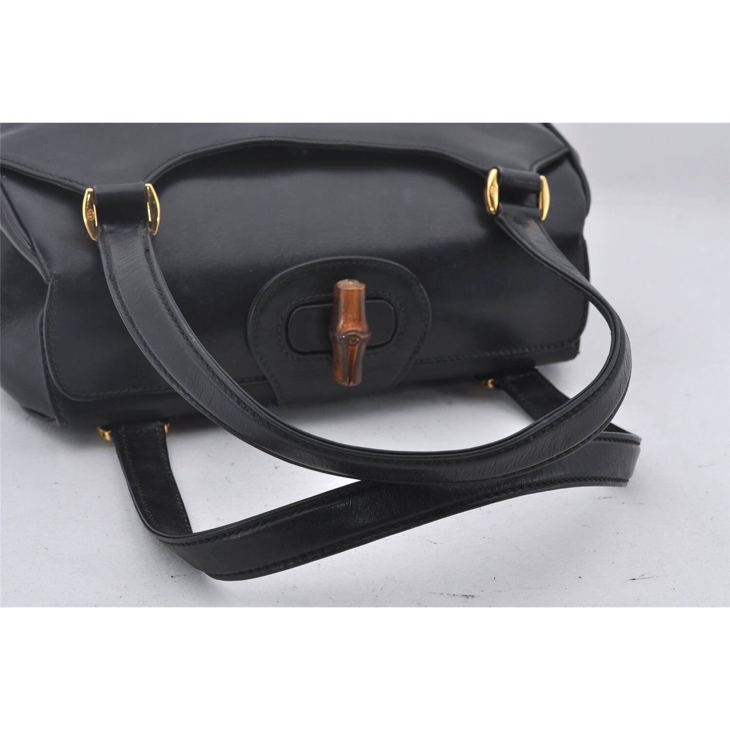 Mod Gucci, black leather shoulder bag with two longer straps, two exterior pockets, a hinged opening, and a gold and bamboo accent clasp