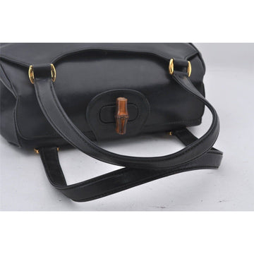 Mod Gucci, black leather shoulder bag with two longer straps, two exterior pockets, a hinged opening, and a gold and bamboo accent clasp