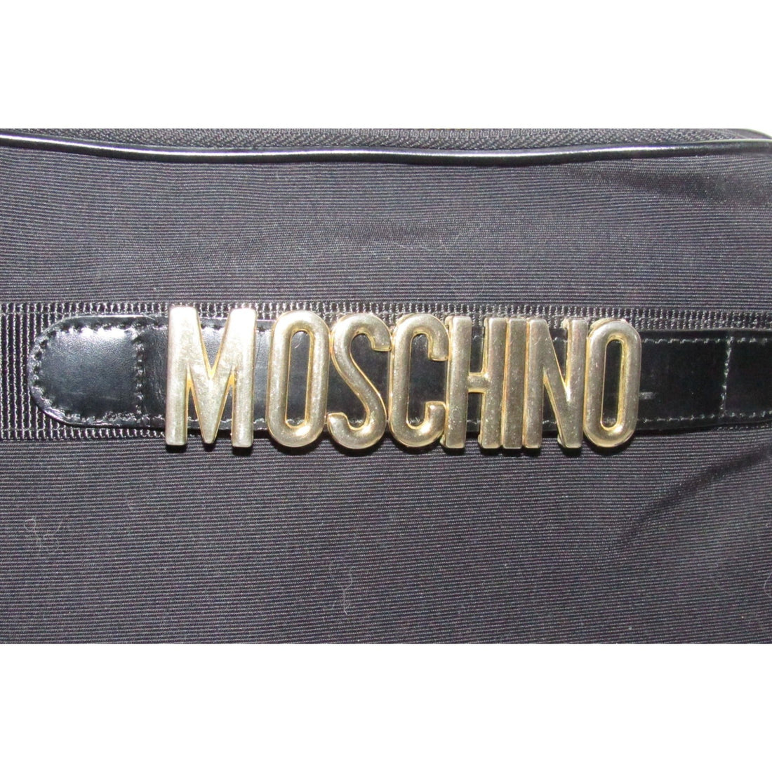 Moschino, black canvas & leather, cross body with a zip top, bold, gold, MOSCHINO letter accents, & a long strap with snaps on both sides