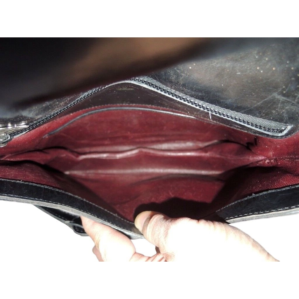 1970s Gucci saddle bag in black leather with muted gold hardware, an expandable bottom, wide shoulder strap, and burgundy leather lining