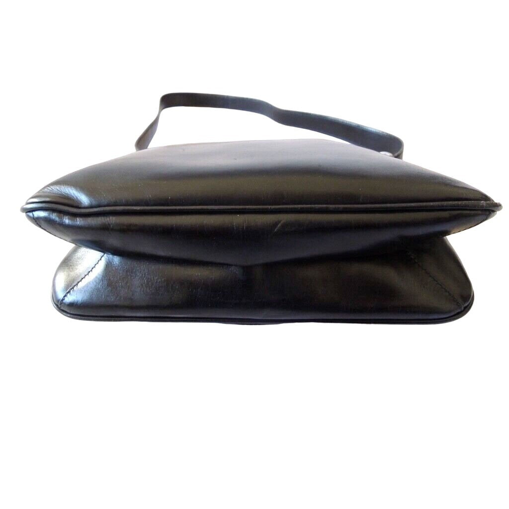 1970s Gucci saddle bag in black leather with muted gold hardware, an expandable bottom, wide shoulder strap, and burgundy leather lining